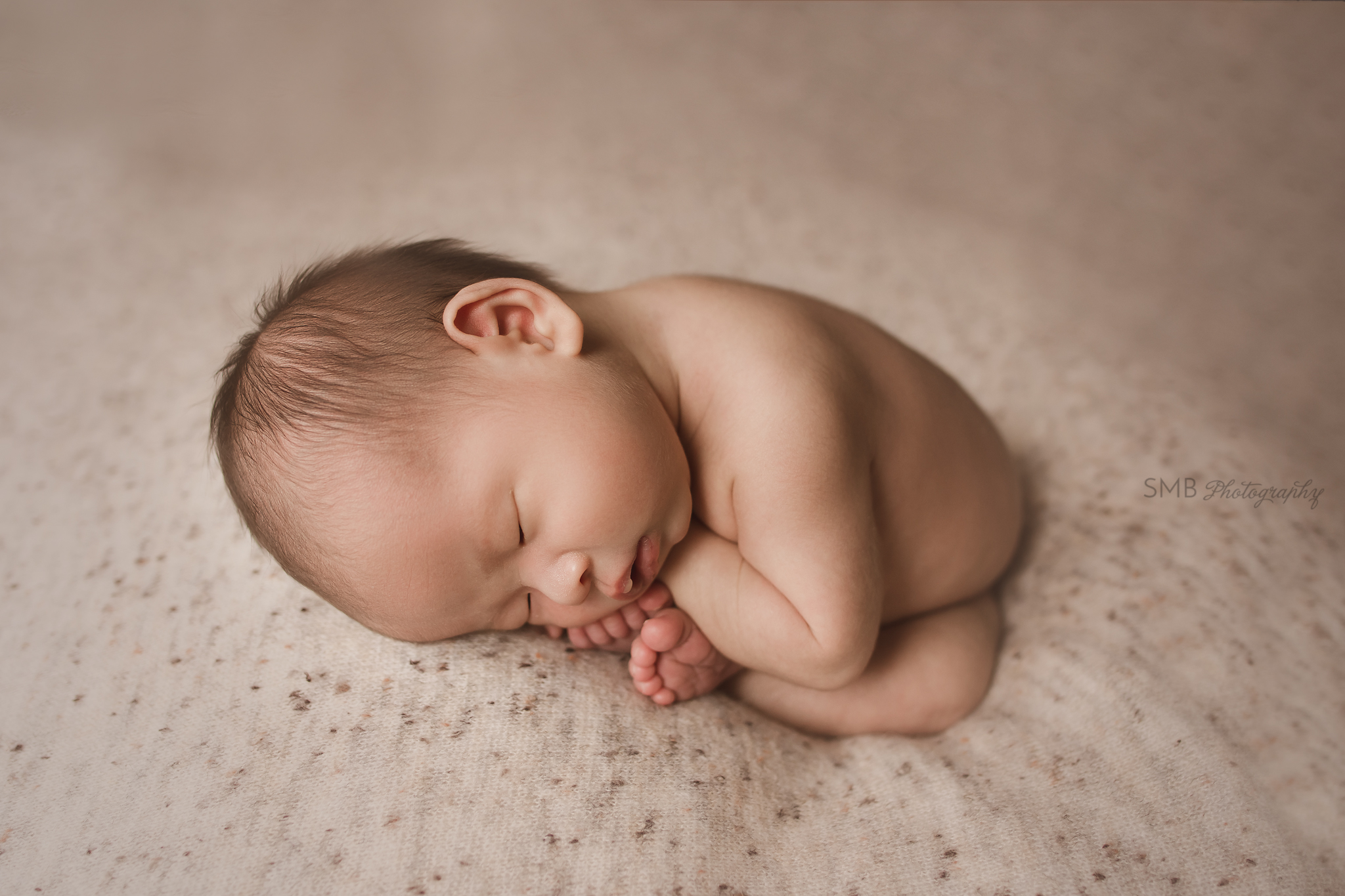 Newborn sleeping on speckled backdrop