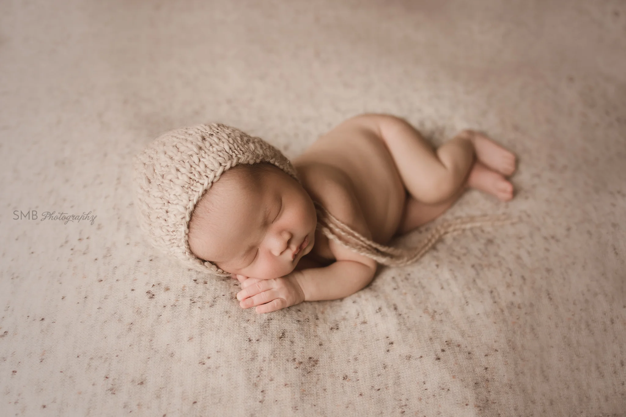 Newborn with hands under cheeks asleep