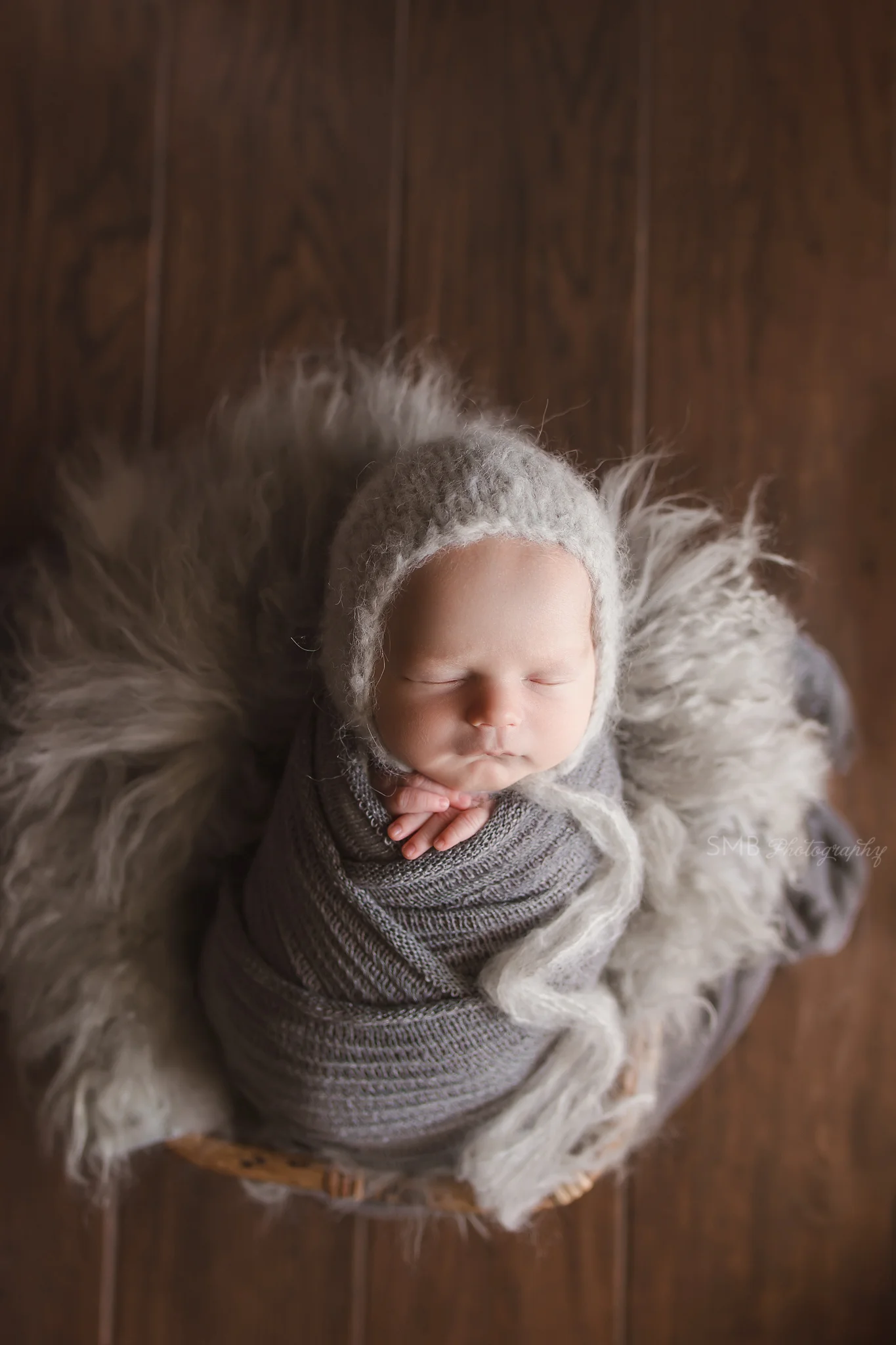 Baby boy wrapped in gray in bamboo basket