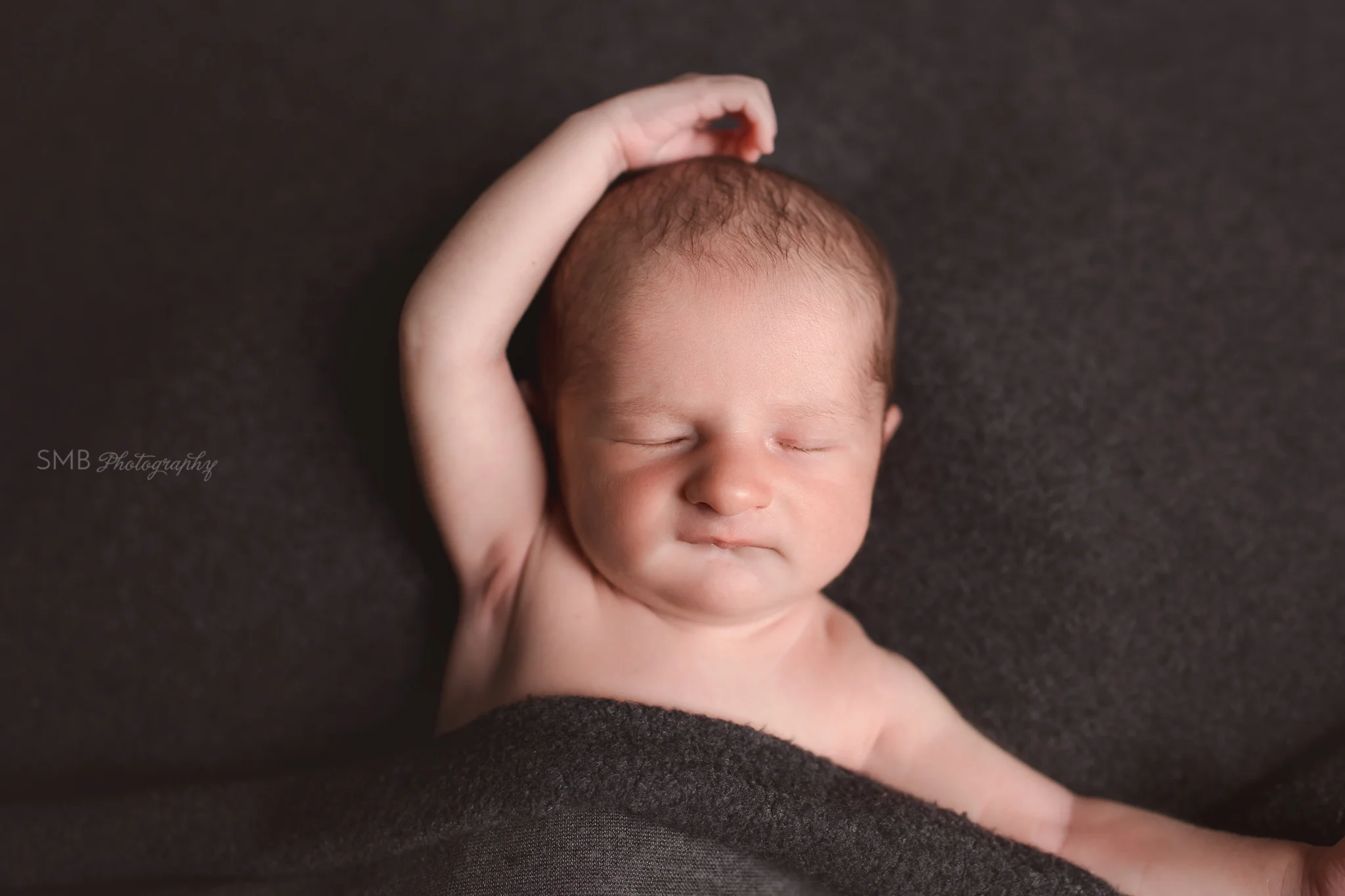 Baby boy sleeping on dark fabric