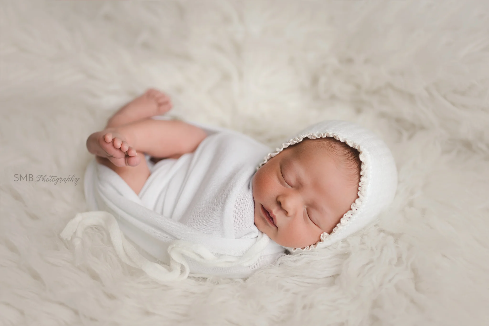 Newborn girl wearing white bonnet