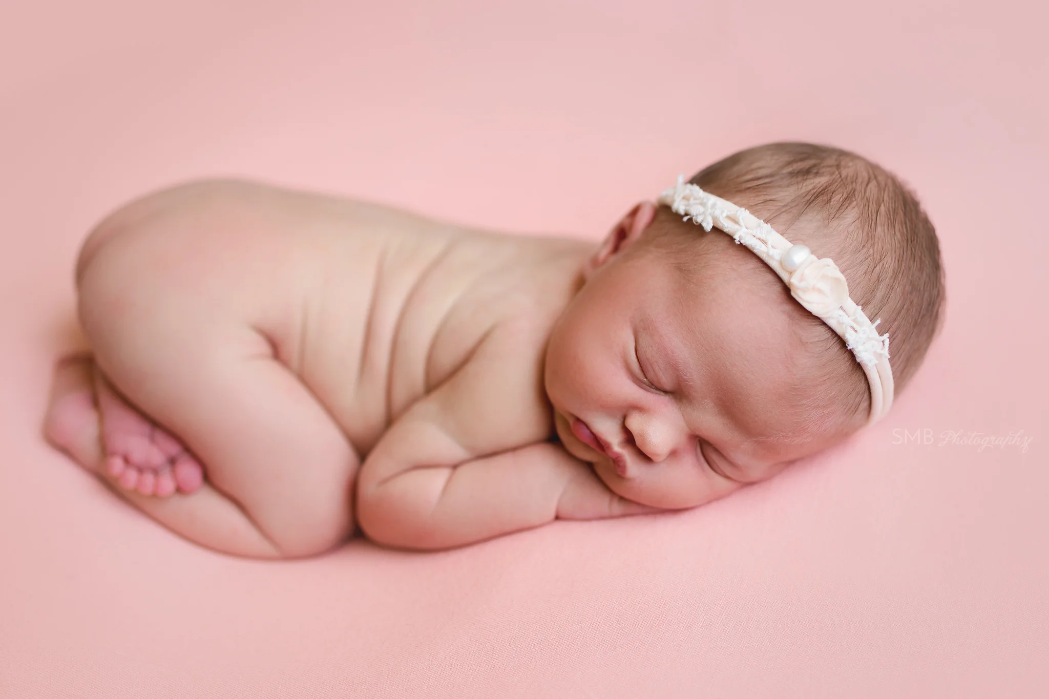 Baby girl wearing headband on peach backdrop