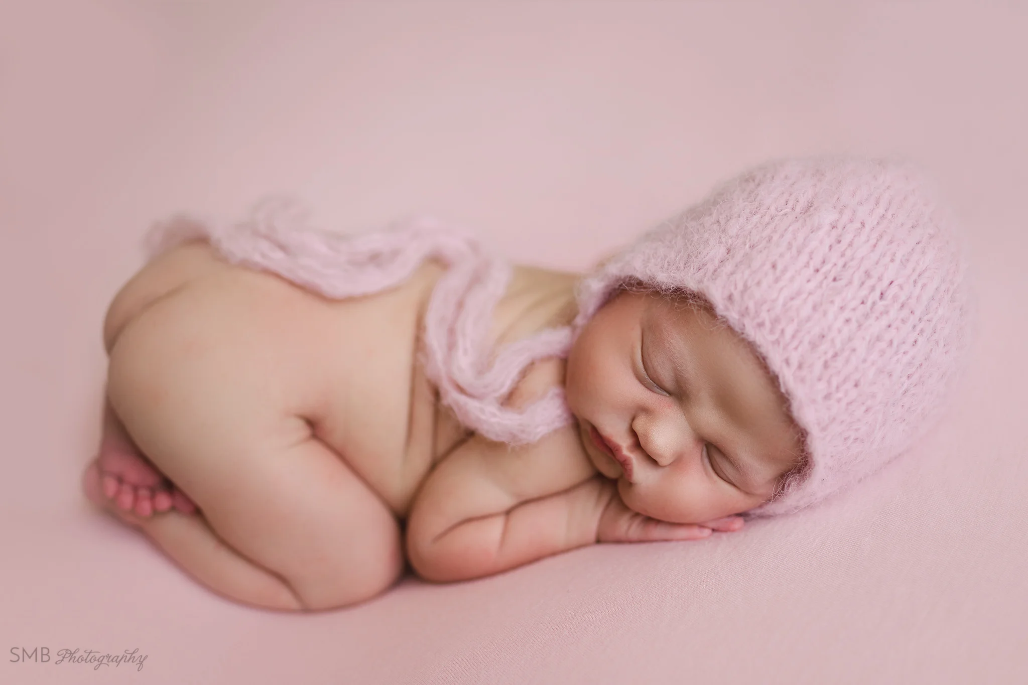 Baby girl in tooshie up pose, wearing pink fuzzy bonnet