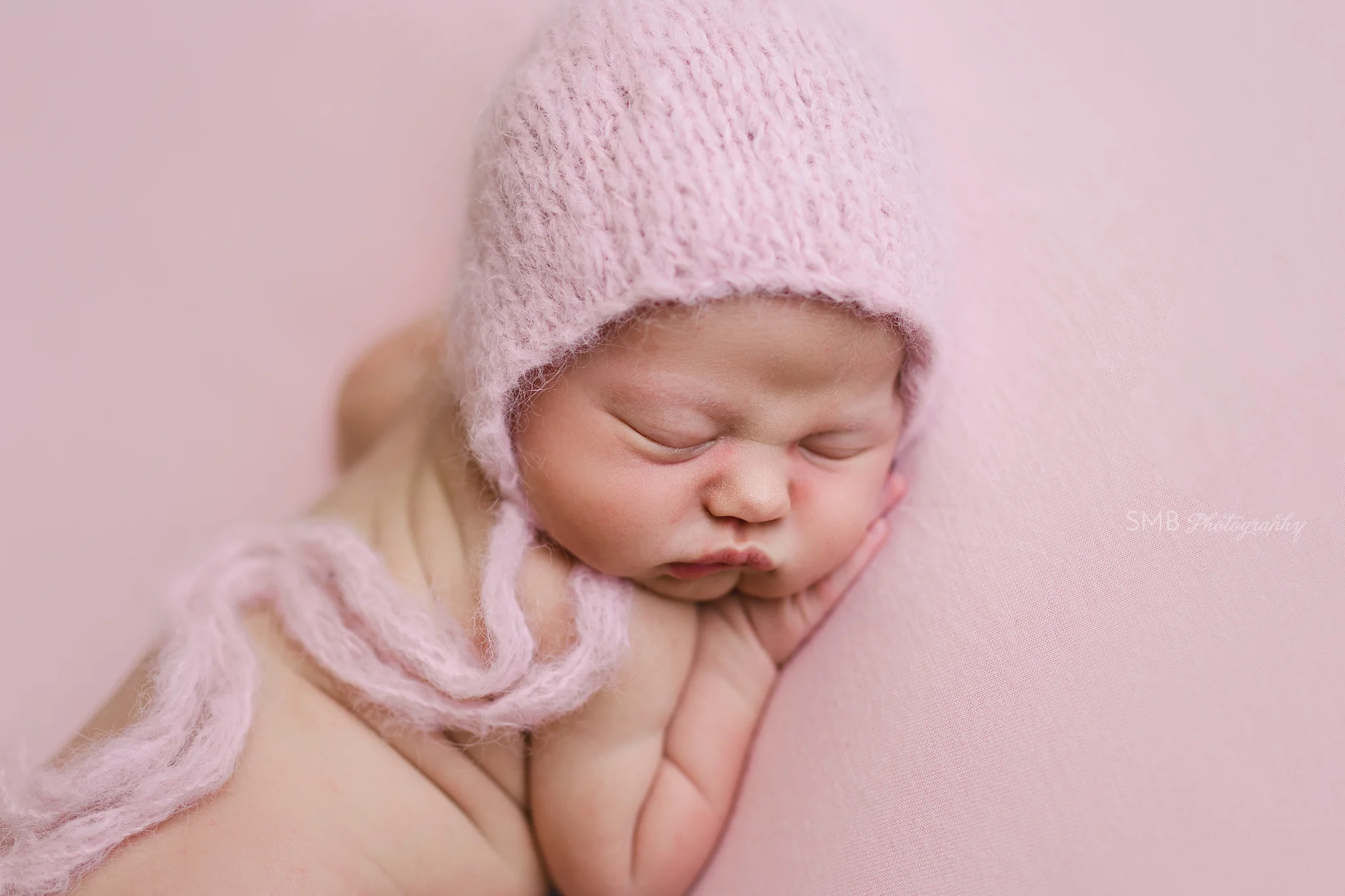 Baby girl sleeping on pink backdrop