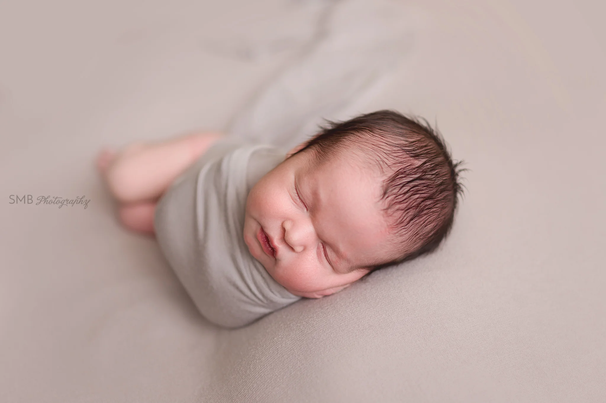 Baby boy wrapped on taupe backdrop