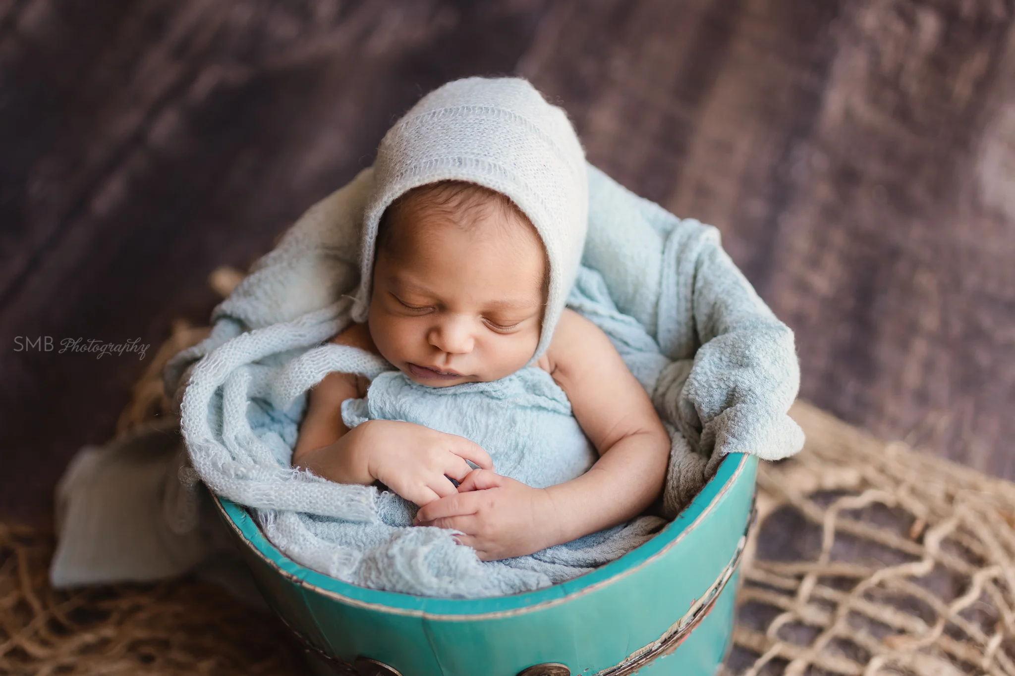 Baby boy sleeping in teal bucket