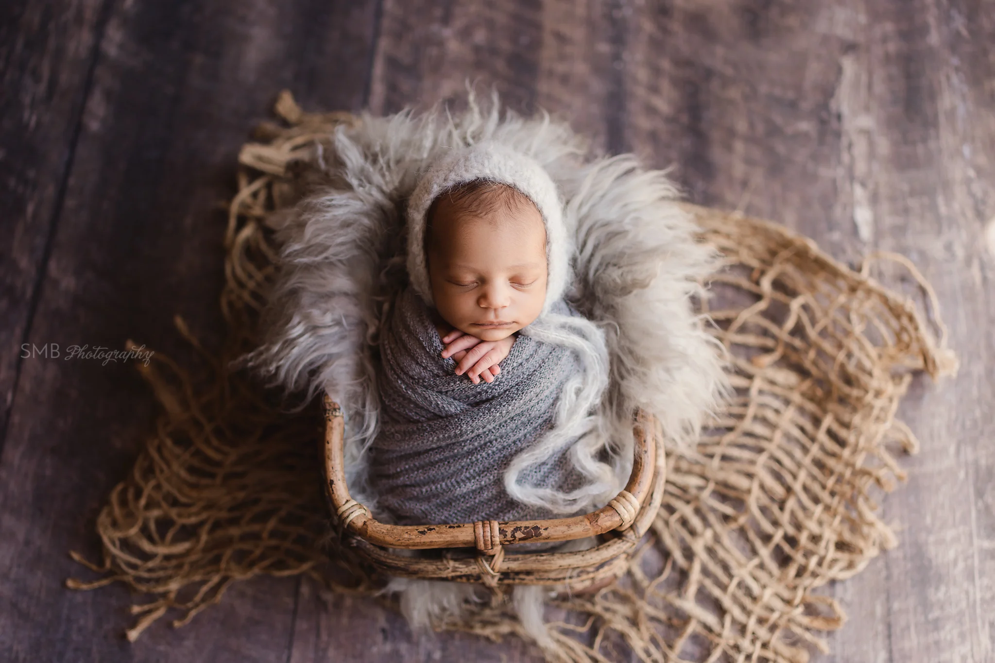 Baby boy in bamboo basket wrapped in textured gray