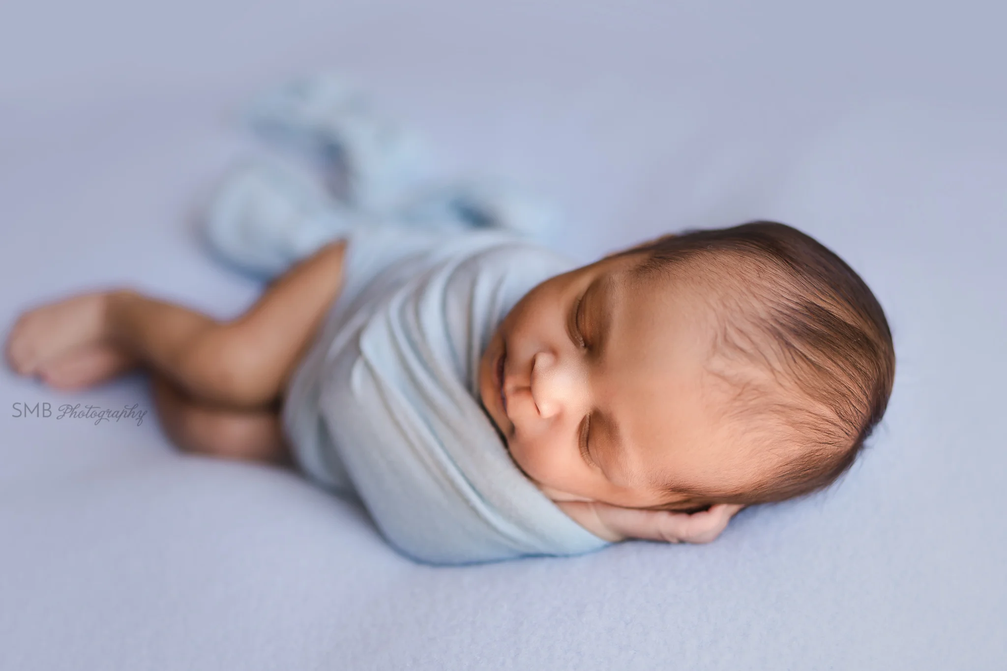 Newborn boy on powder blue backdrop