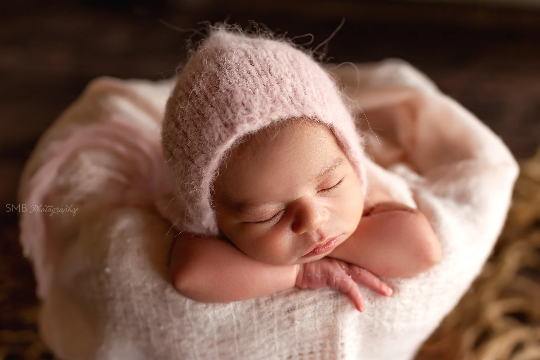 Baby girl facing forward in pink fuzzy bonnet