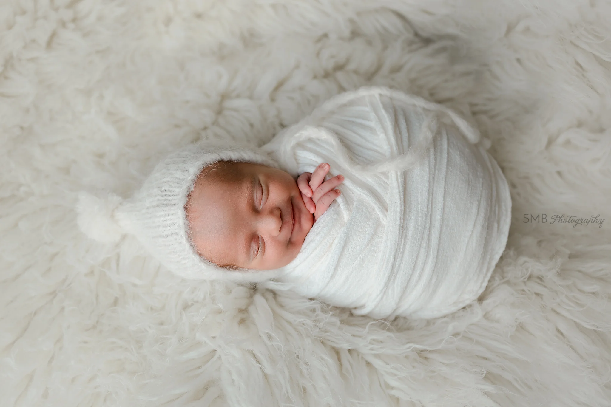 Sleeping newborn wrapped and smiling