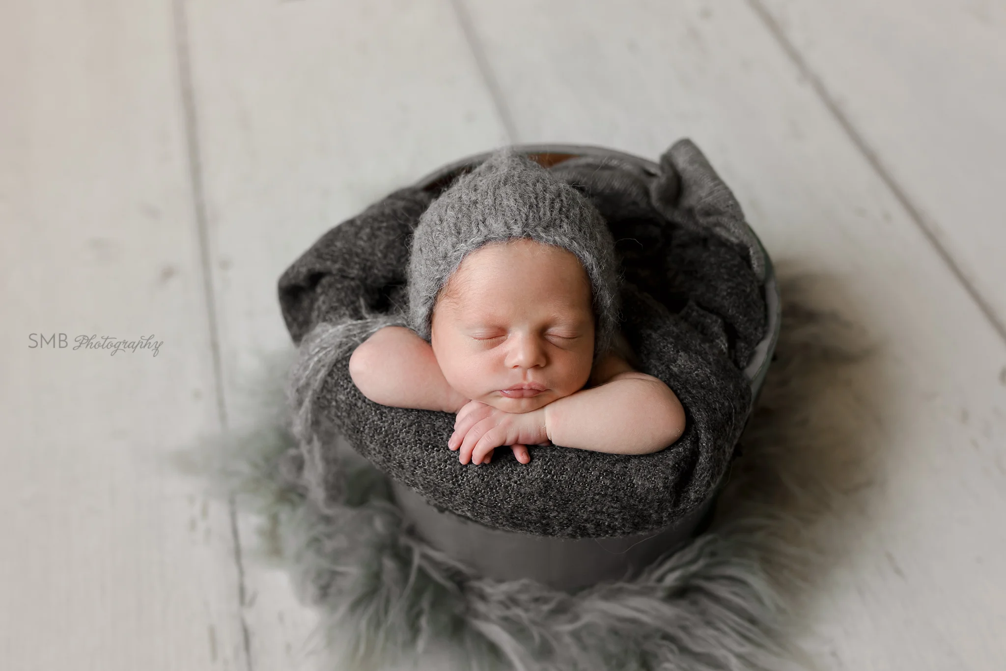 New baby facing forward in gray wood bucket