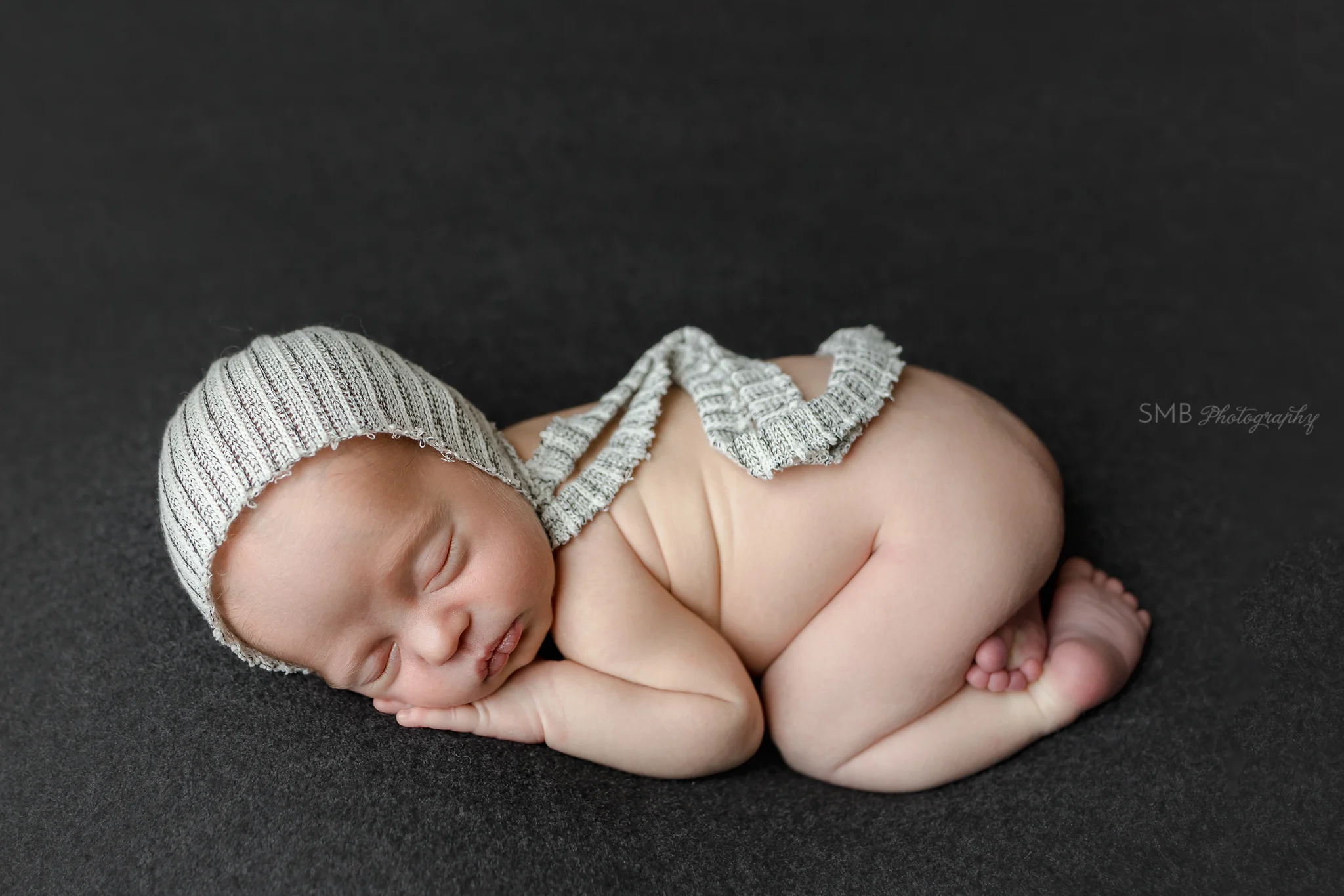 Baby boy sleeping on charcoal colored backdrop