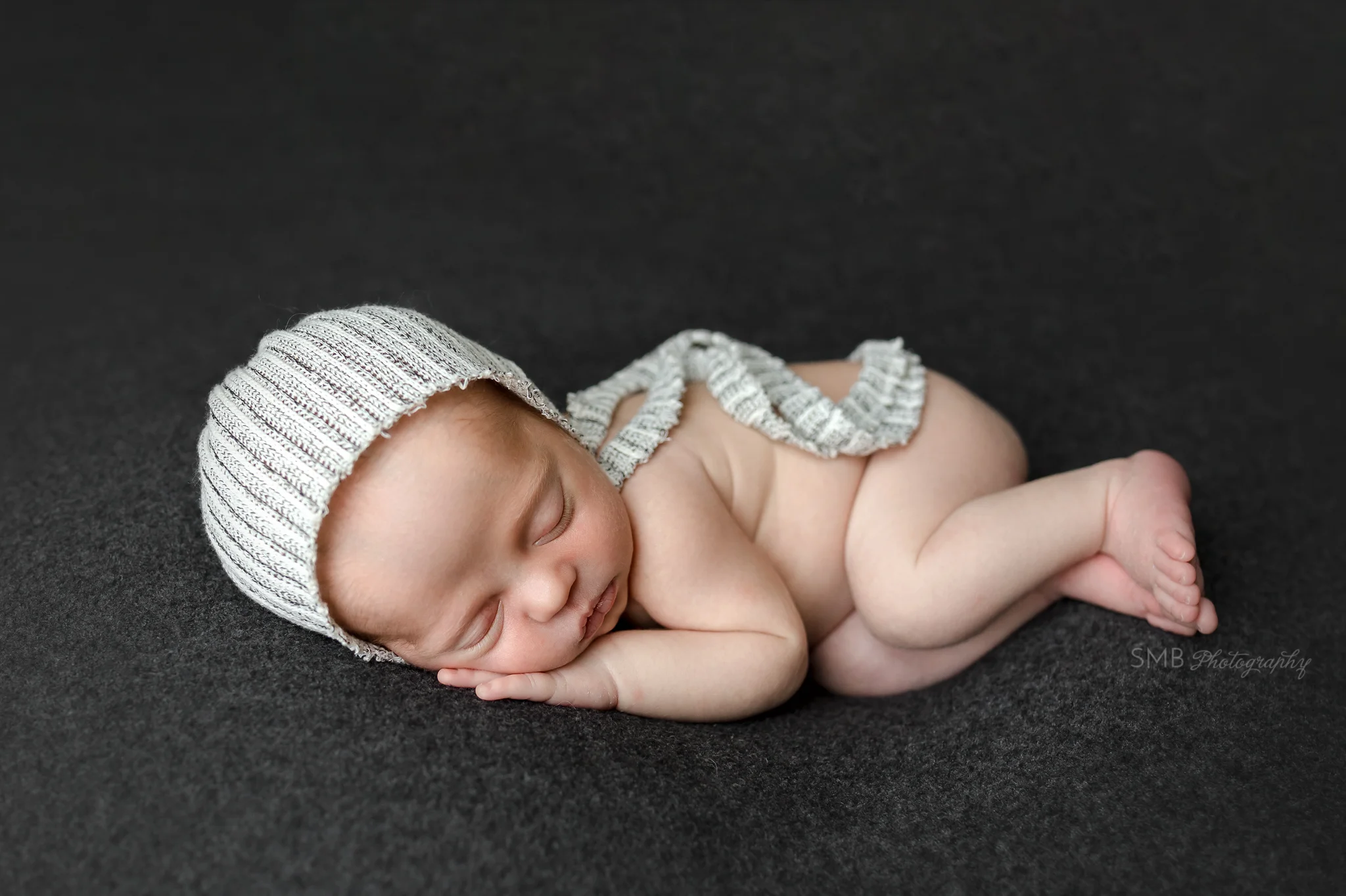Baby boy wearing bonnet with hand under cheek