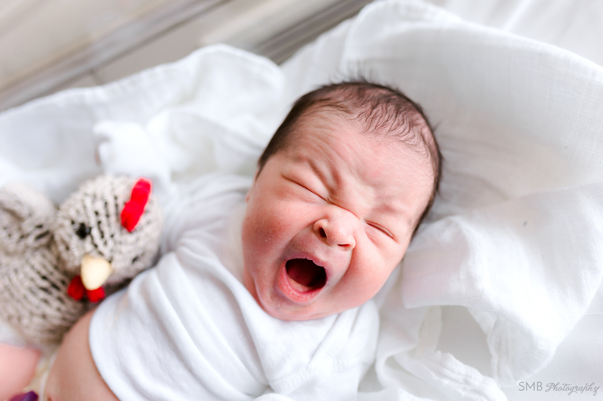 Baby yawning in hospital bassinet