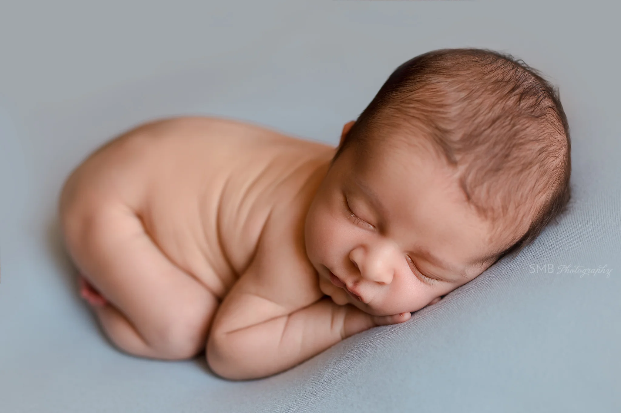 Newborn sleeping on belly on baby blue blanket