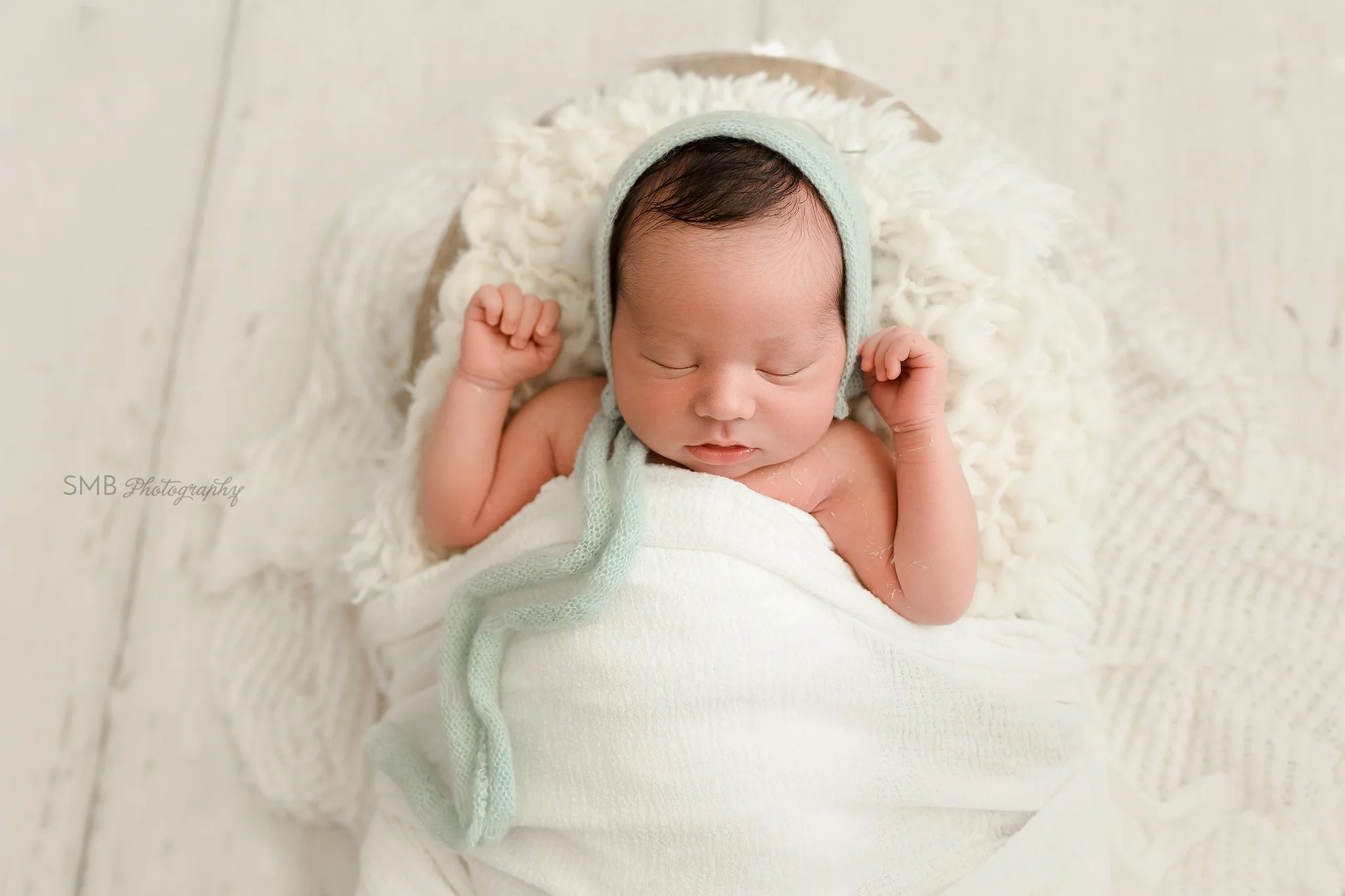 Newborn boy wrapped sleeping in wood trencher