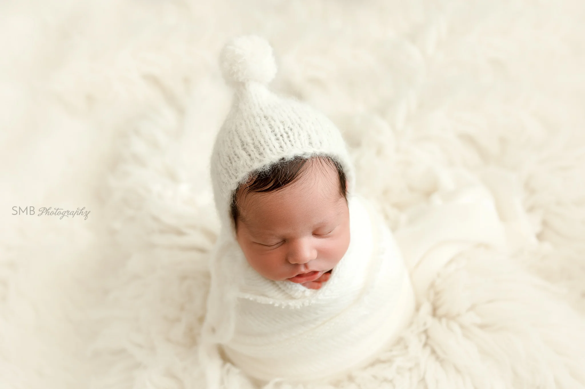 Baby wrapped in cream on white flokati