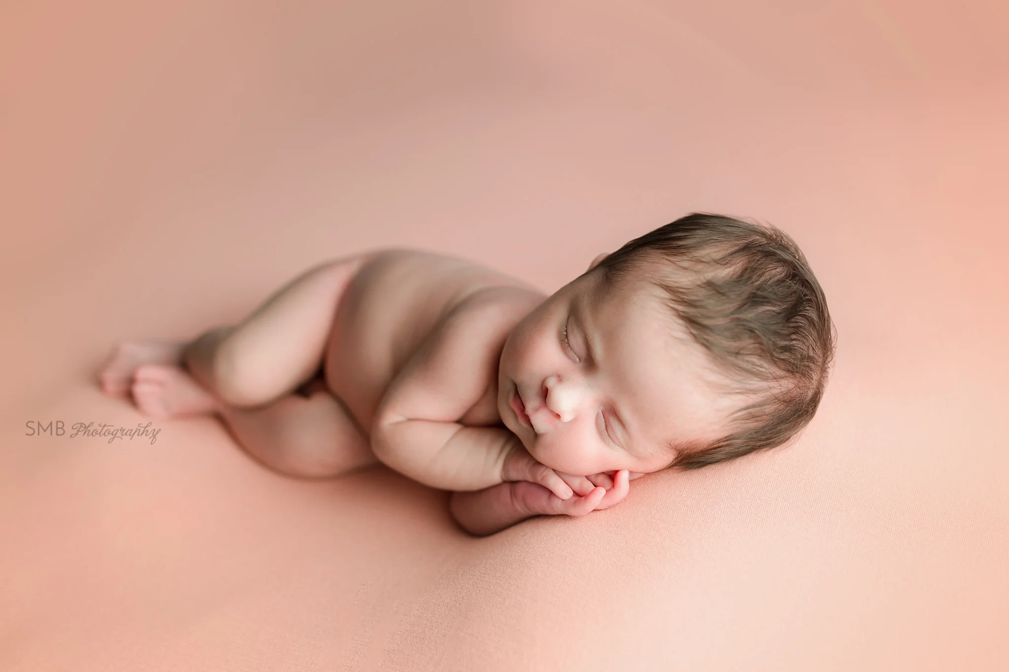 Baby girl sleeping on peach backdrop