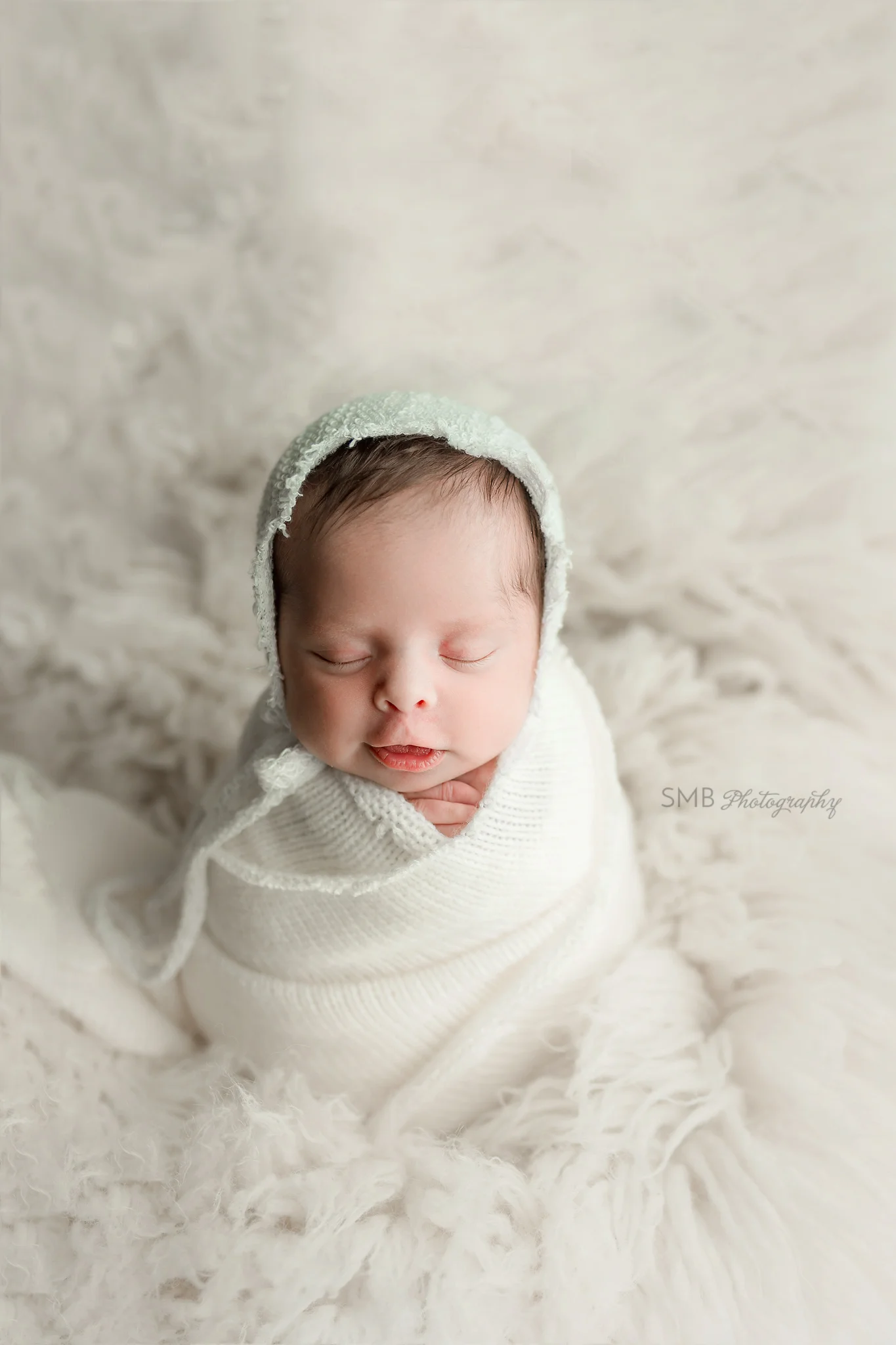 Newborn baby girl smirking on white fur