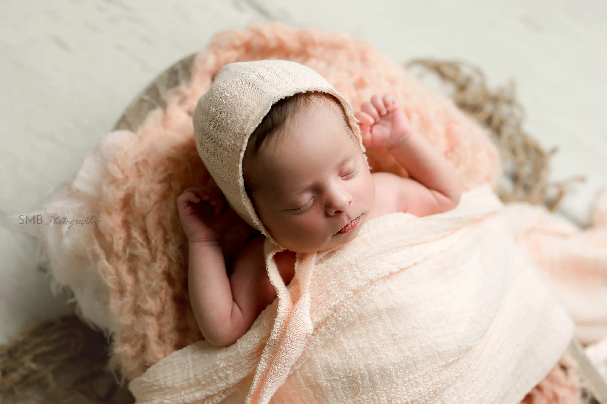 Baby girl tucked in wearing peach hat