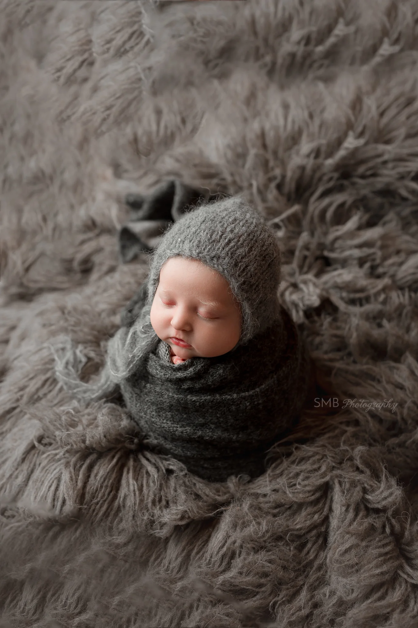 Newborn wrapped in charcoal wrap on gray fur