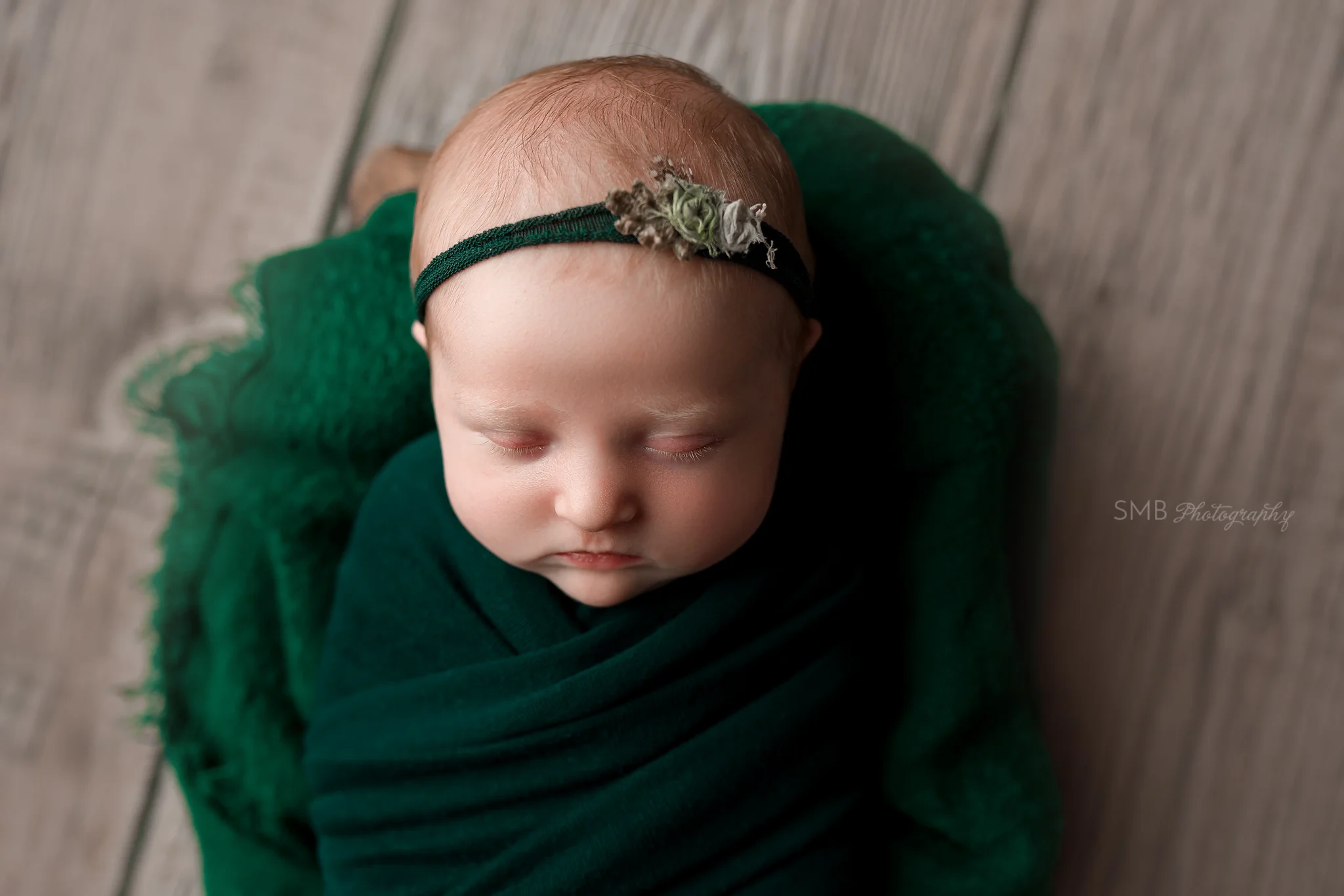 Newborn girl wrapped in hunter green