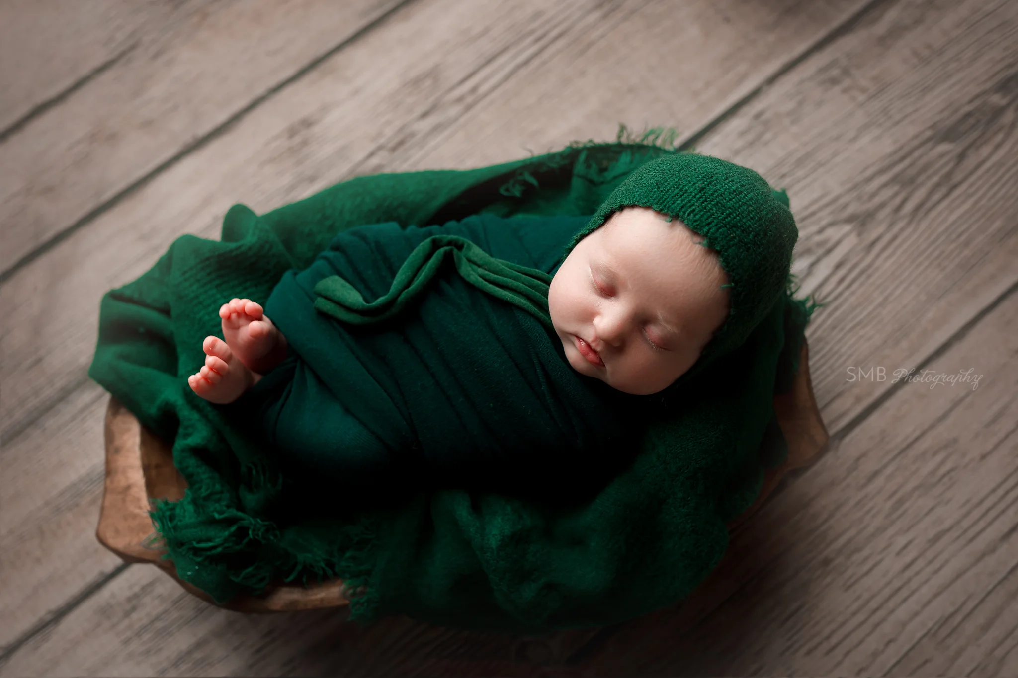 Baby wrapped up in wood trencher in hunter green