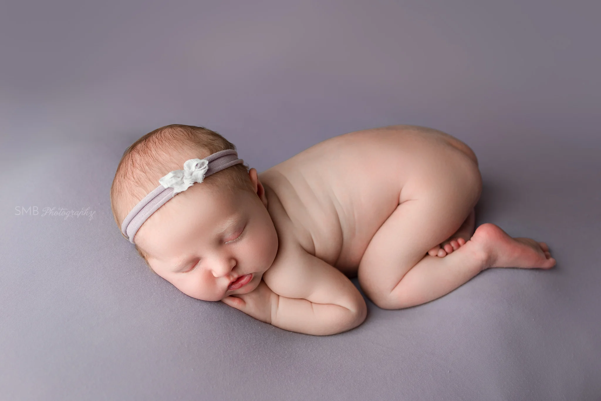 Baby girl on purple backdrop in bum up pose