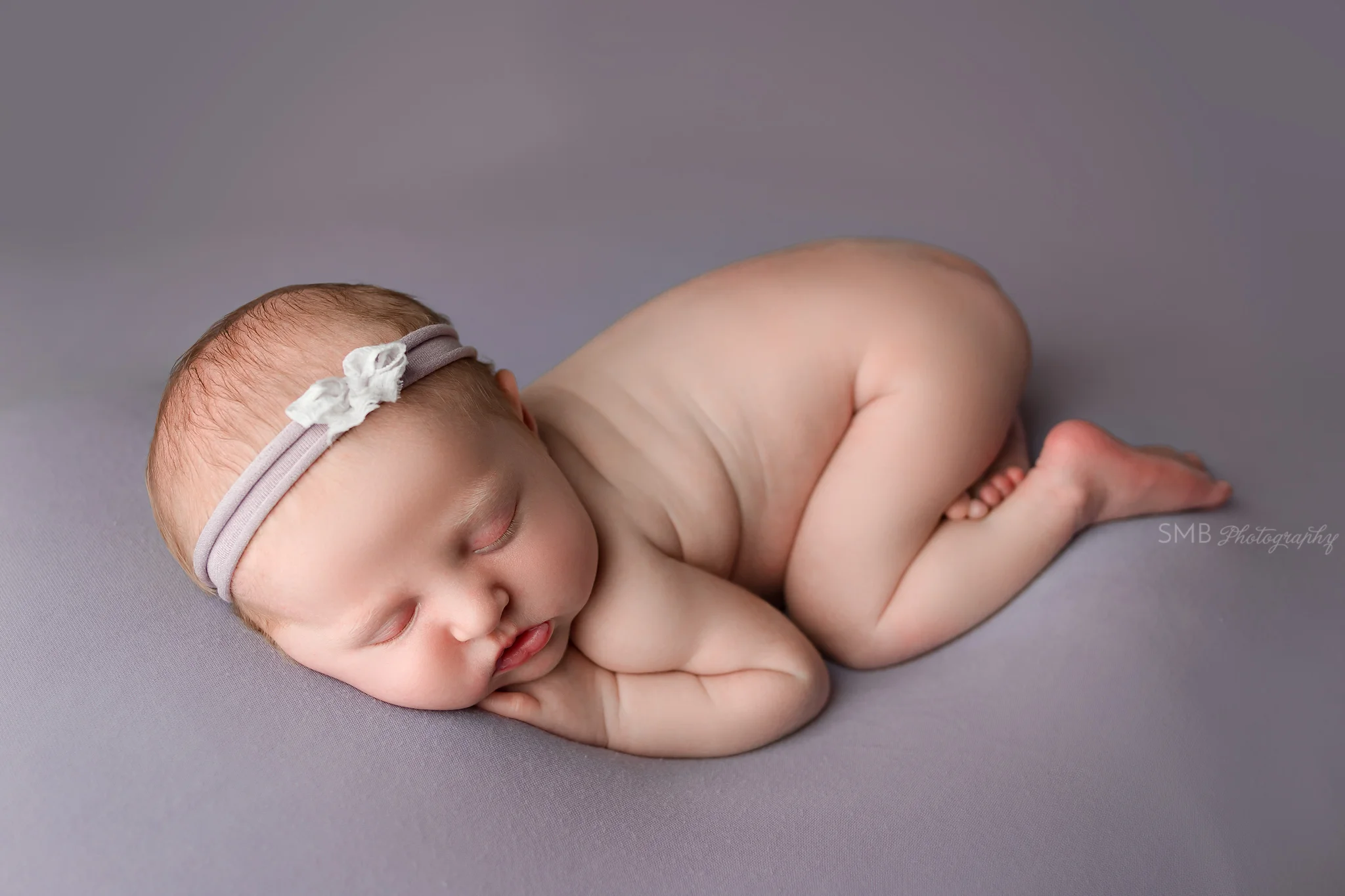 Newborn girl wearing purple headband