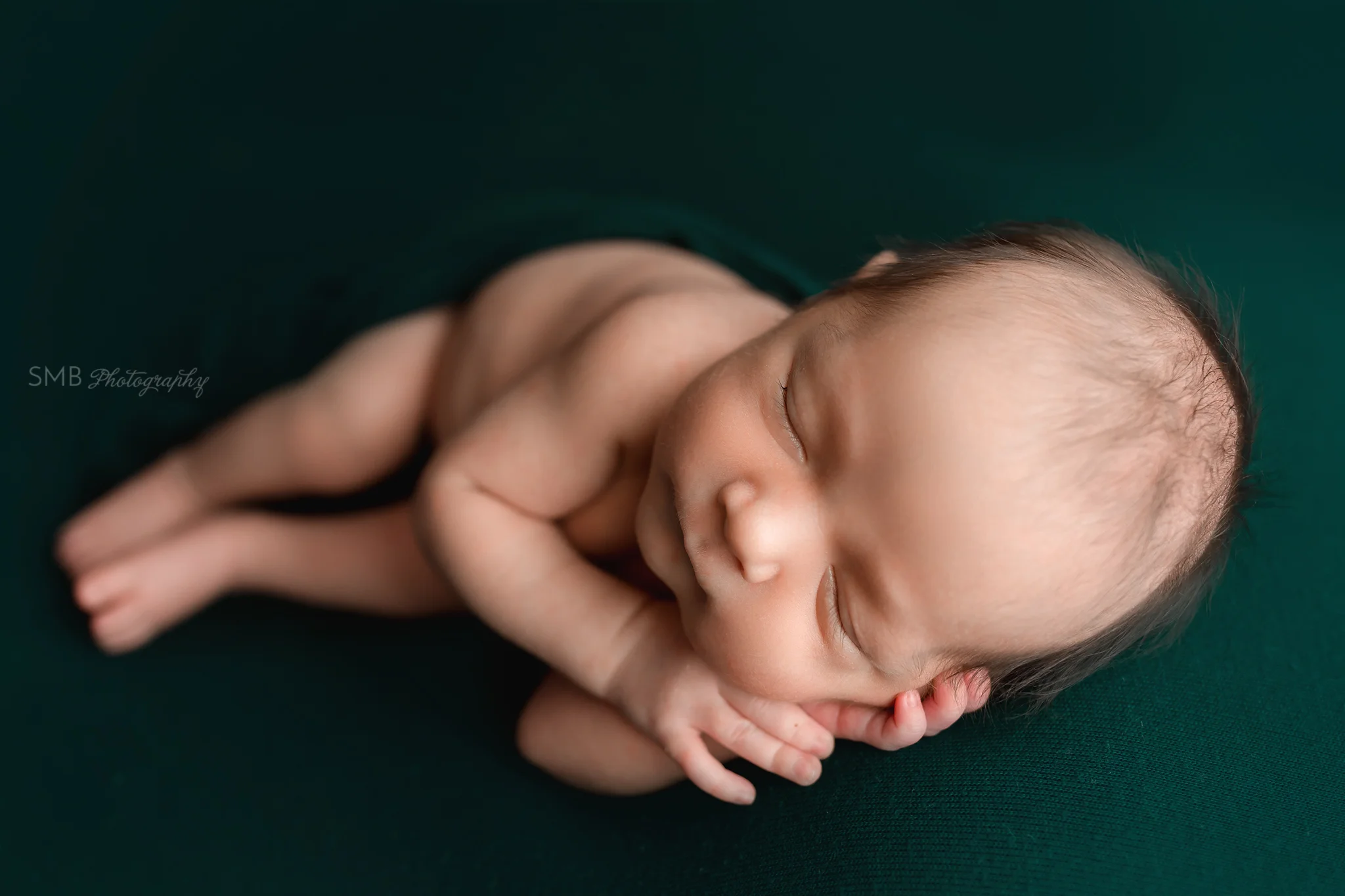 Baby boy sleeping on hunter green backdrop