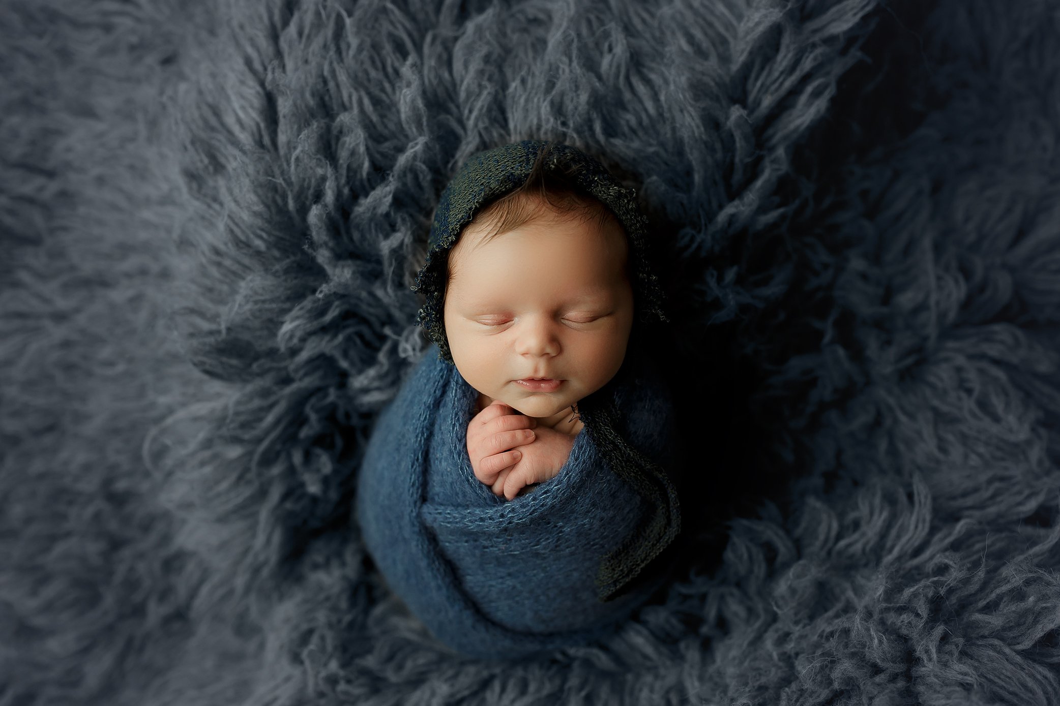 Baby boy wrapped on blue flokati