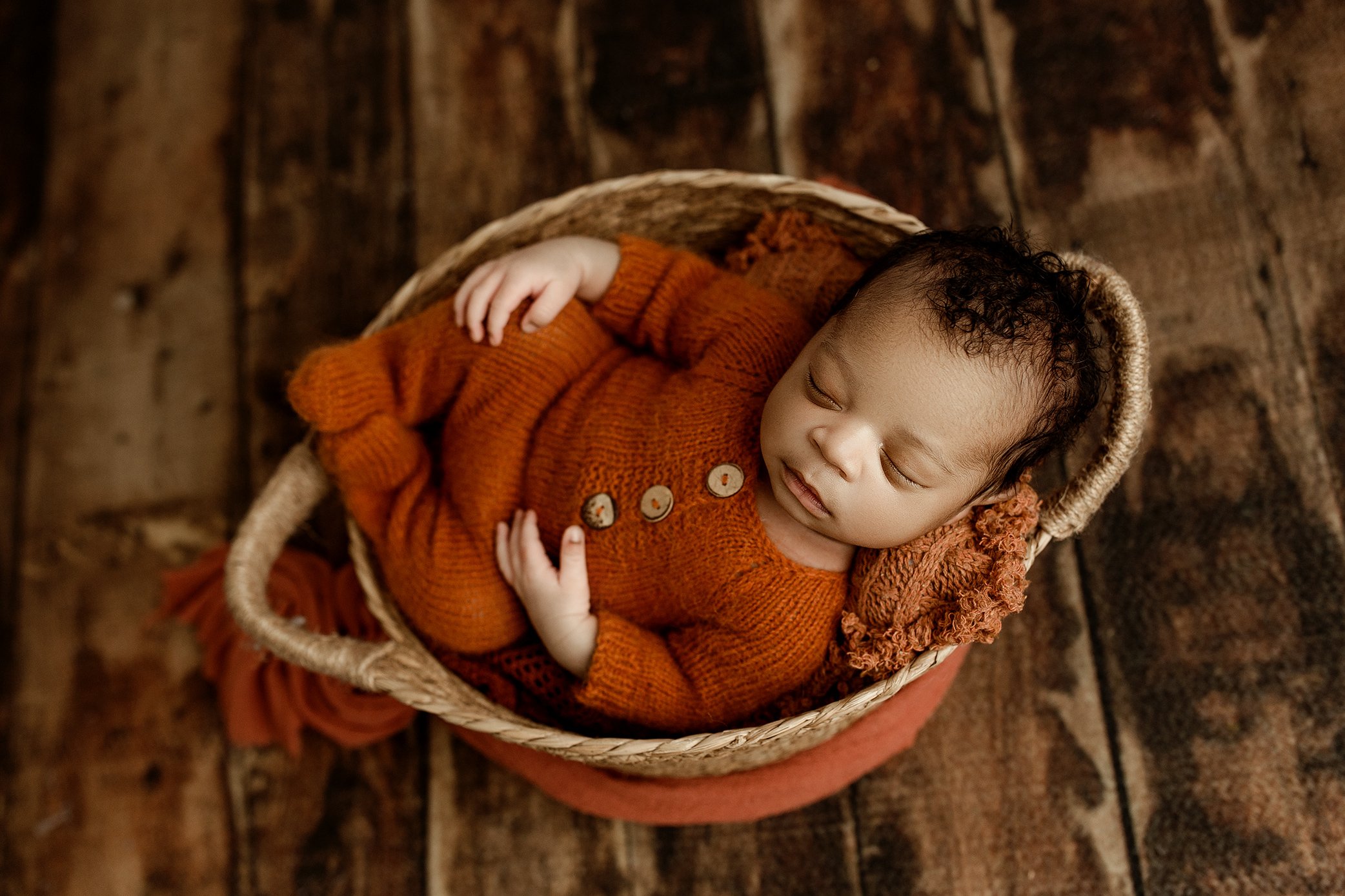 Baby boy wearing rust colored romper