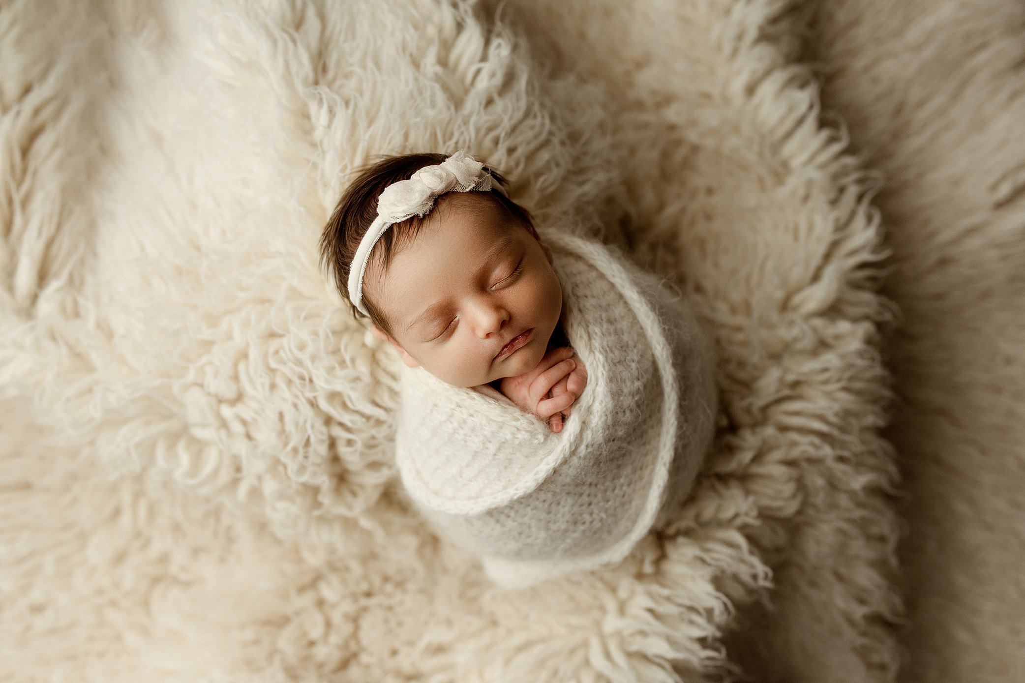 Baby girl wrapped on white flokati