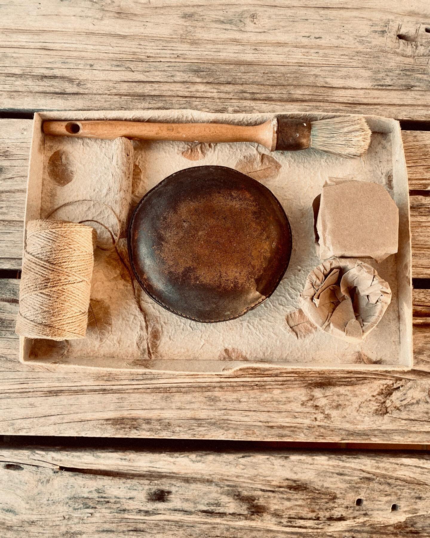 A box of necessities. Completely unstyled, this is an old box lid into which I think Ben, or anyone, has placed things that belong to me. A brush, an artists elbow support, a piece of driftwood, two brown paper packages, some string. A lid made of mu