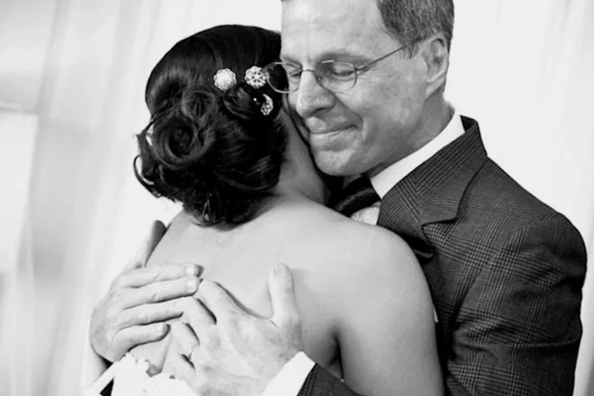 Father of the bride sharing a tender embrace on her wedding day, black and white wedding photography