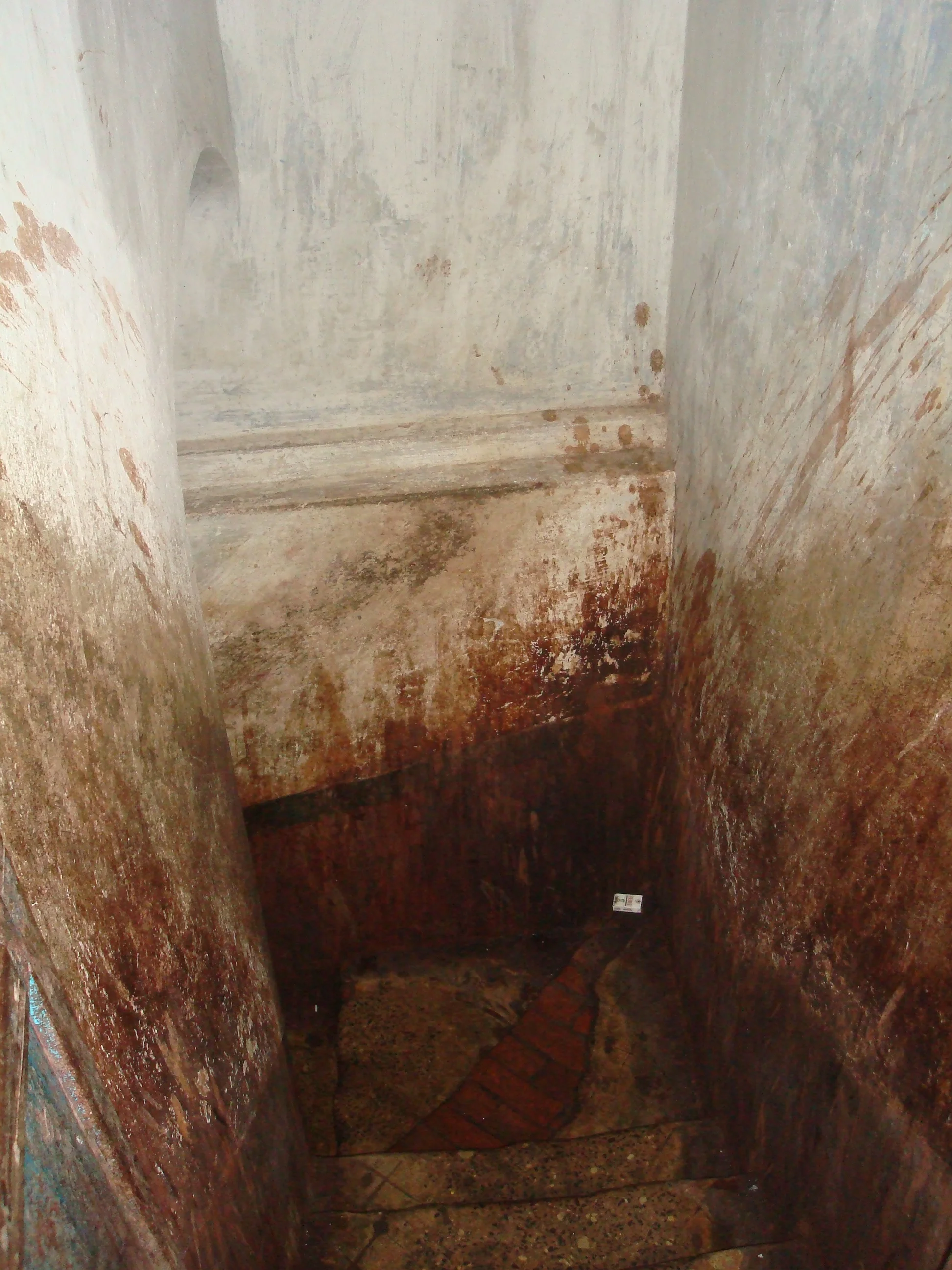 The stairwell of a brothel covered in spit and filth.