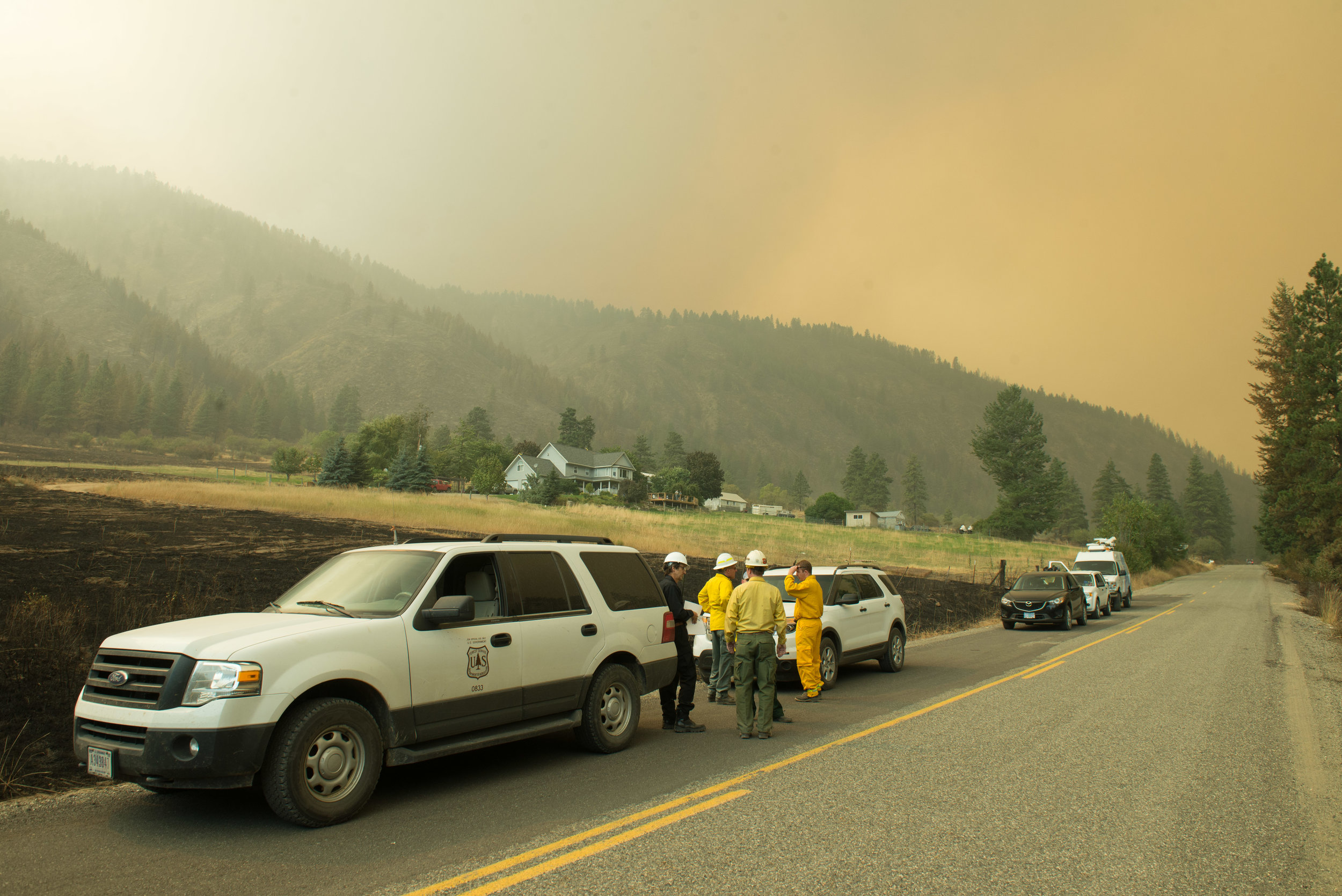  Journalists and Firefighters observe smoke plumes rising from the Okanogan Complex Fire on Salmon Creek Road, South Central Okanogan County, Sunday August 23, 2015. Salmon Creek road contains a number of residential structures that fire crews sought