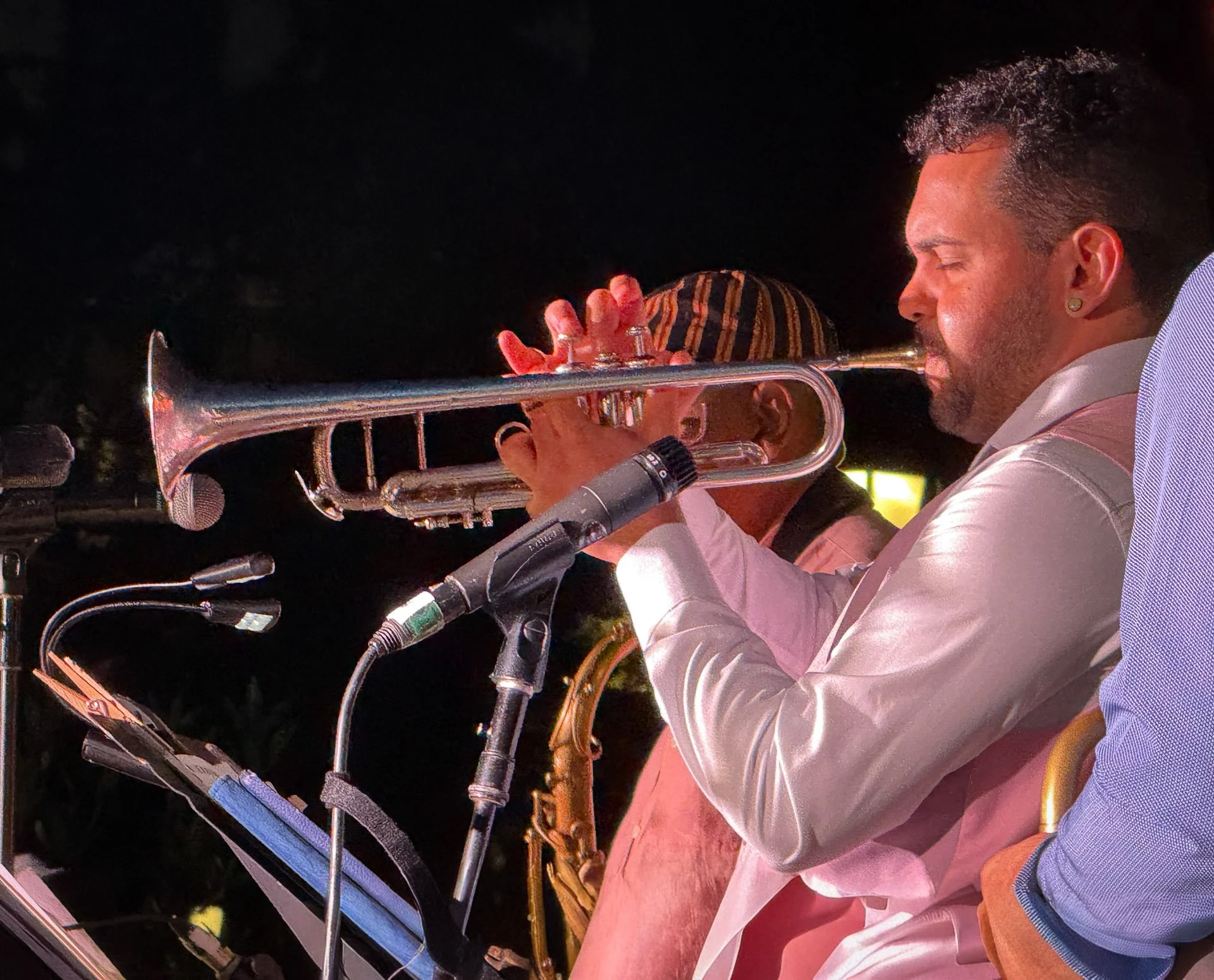 A close up of Latin Grammy–nominated trumpeter, composer, and bandleader Kali Rodriguez PeñaItai performing on the trumpet (facing left). Photo by Sally Blair.