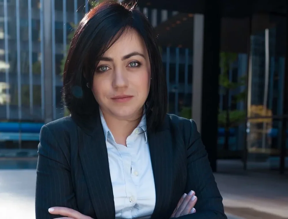 Irina Popa-Erwin, founder of The NYC Life Coach, in a dark suit with her arms crossed