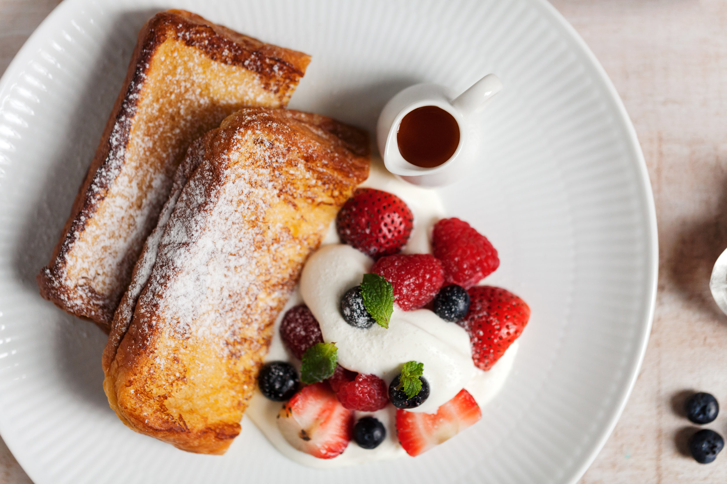 【季節水果法式吐司】 (French Toast With Seasonal Fruit) 把早晨剛出爐的布里歐吐司浸入添了牛乳的蛋液中,讓它安靜睡一天,吸飽了蛋汁的吐司麵包開始蓬鬆、軟嫩,成了與平常吐司截然不同的存在。第二天,將吐司取出煎得嫩黃上色,撒上糖粉與水果、楓糖一起遞給你,切開,擁有雲朵般細嫩的質地、嚼進口中的則是品質好的雞蛋、牛乳與糖,這是最不令人厭倦的醇郁滋味!