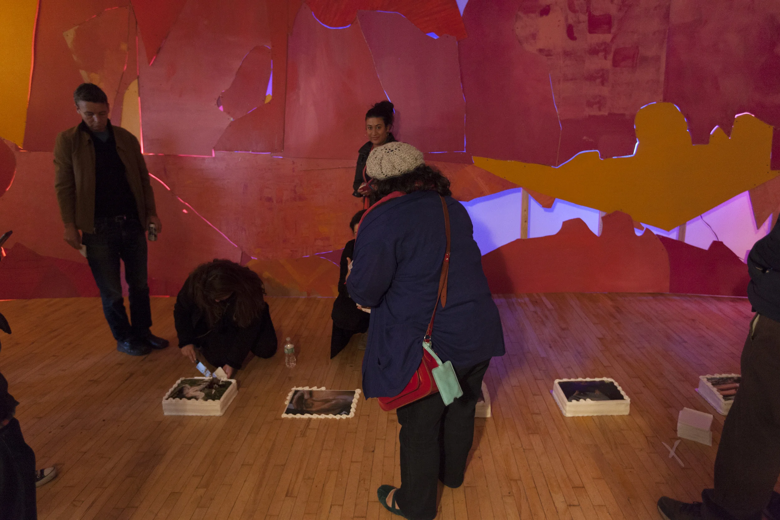 Viewers cut into Roxanne D. Crocker’s CAKE , set against the backdrop of Lisi Raskin’s Flat Screen (Pink Wall) at the opening of the group show you know it when you feel it as part of Recuperative Tactics , Art in General, April 19, 2014. Image credit: Steven Probert