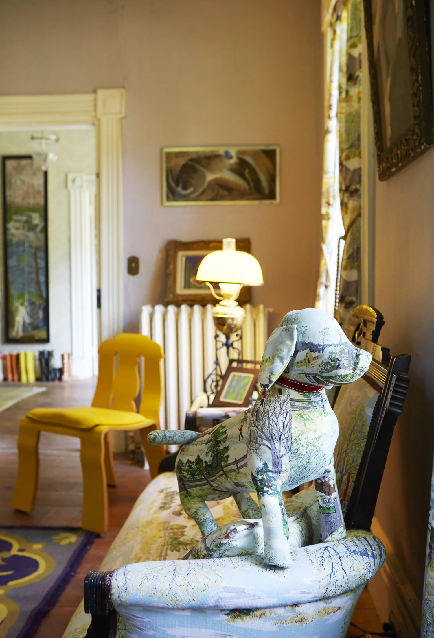 Empire chair by Robert Venturi and Denise Scott Brown. Grandma Moses fabric Doggie doll pillow by Peyton Jefferson.