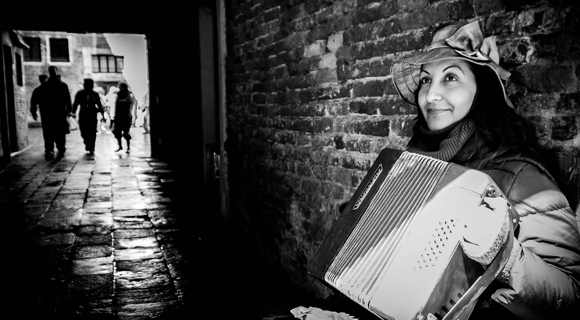 I photographed this busker in the half light of an alley following a wet and windy morning in Venice. The combination of the light, the wet cobbles and the people walking towards her makes a story and one unlikely to be photographed by others that day.