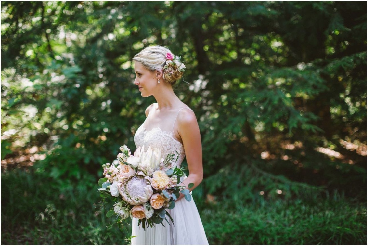 Beautiful Bride with Flowers in her Hair. Her bouquet includes King Protea, Juliet Garden Roses, Lisianthus, Stock, Blushing Bride Protea, Jasmine vine and Eucalyptus.
