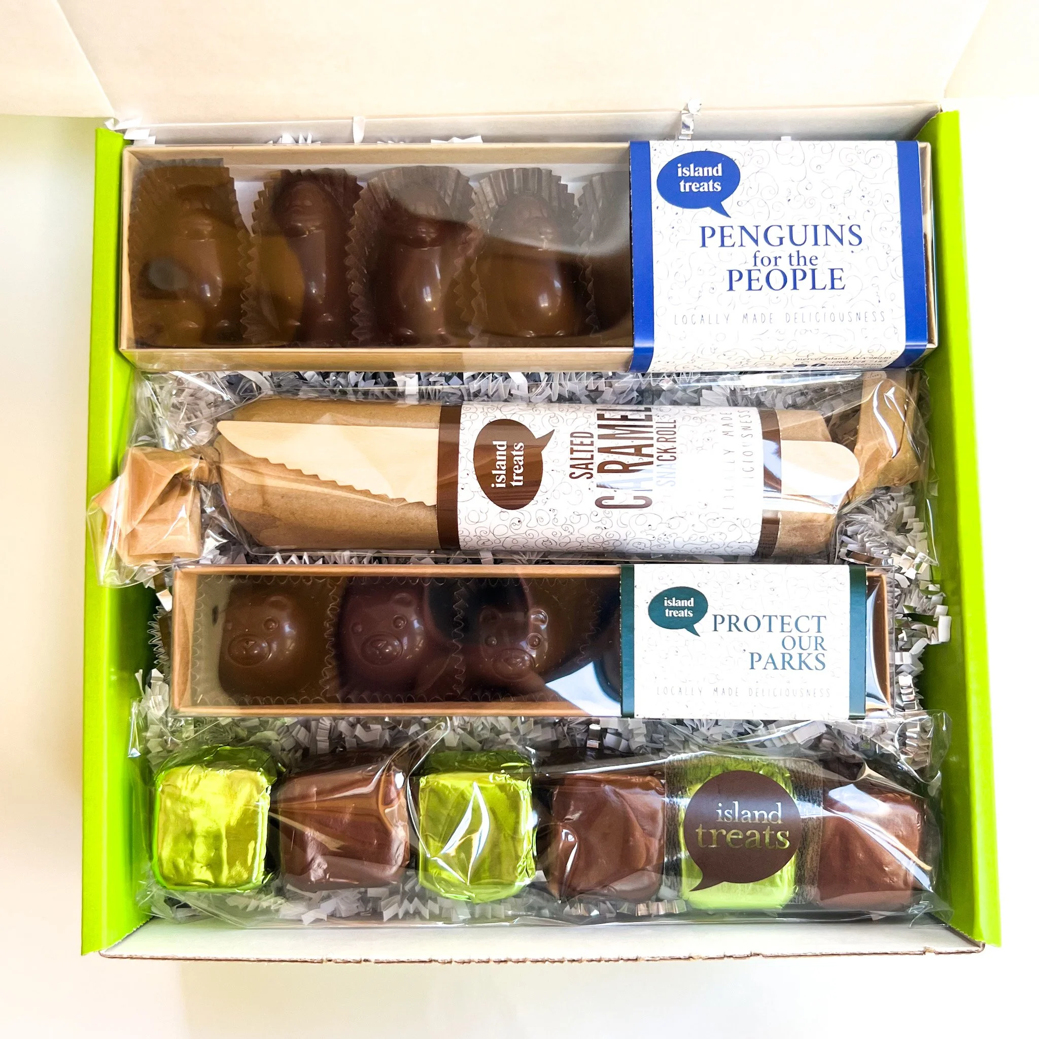 A box of chocolate penguin-shaped treats labeled 'Island Treats Penguins for the People,' with a window showing the chocolates inside.