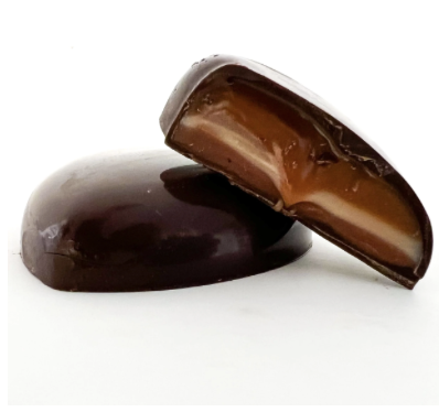 Cross-section of a handcrafted filled chocolate from a Seattle chocolate maker, showing layers of caramel and ganache inside dark chocolate.