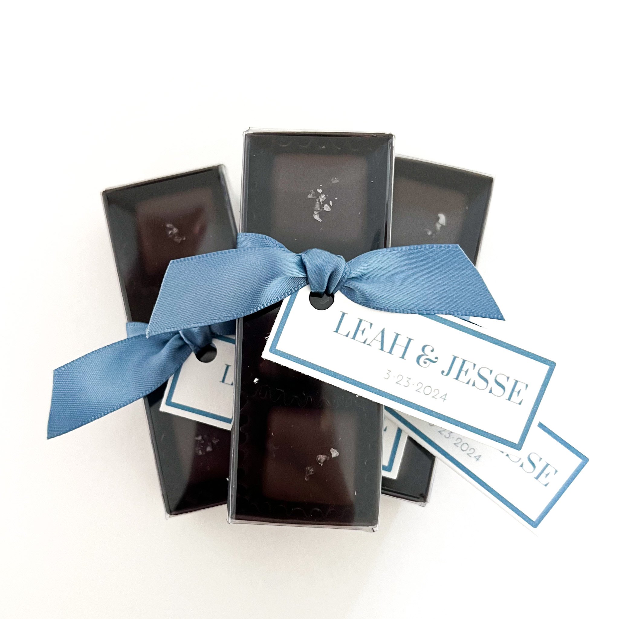 Personalized chocolate caramel wedding favors from a Seattle-based chocolatier, featuring handcrafted chocolates tied with blue ribbon.