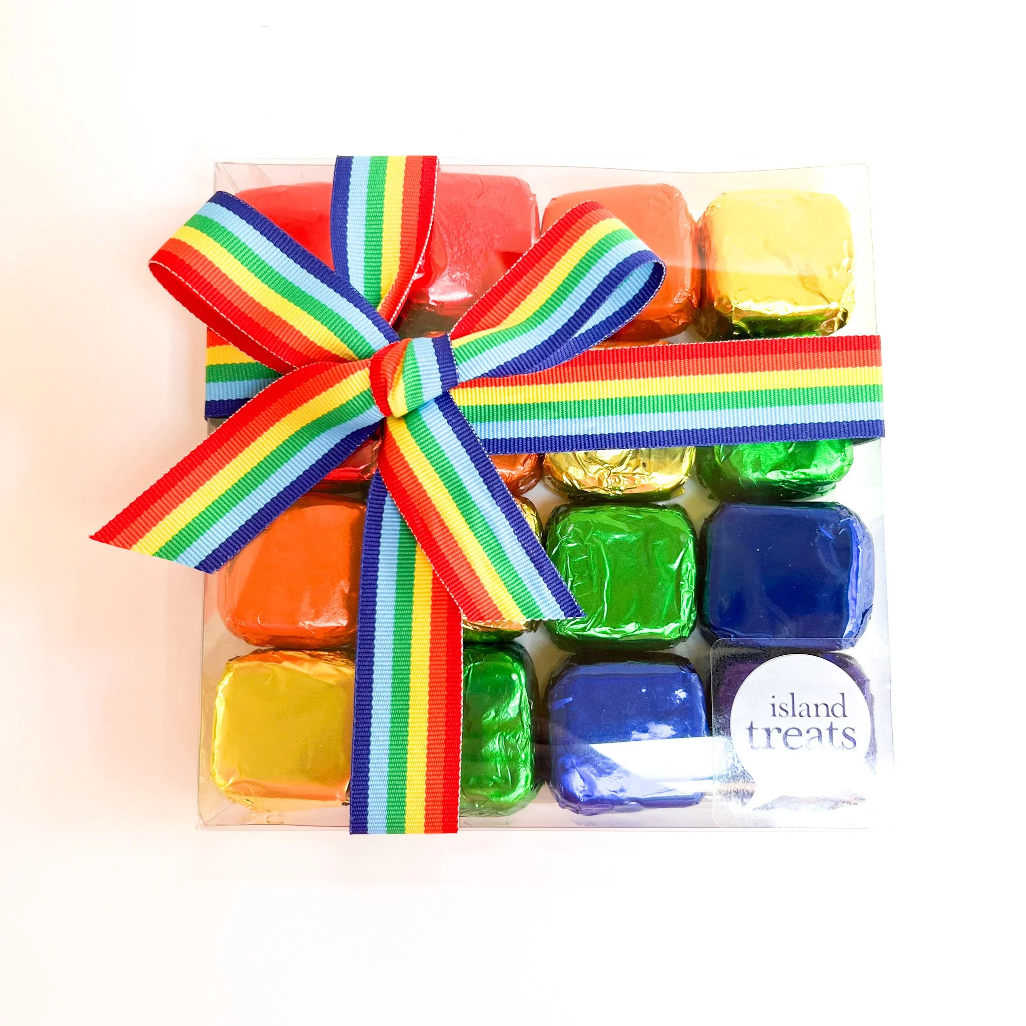 Colorful wrapped candy bars in a clear plastic box tied with a rainbow striped ribbon, labeled 'island treats'.