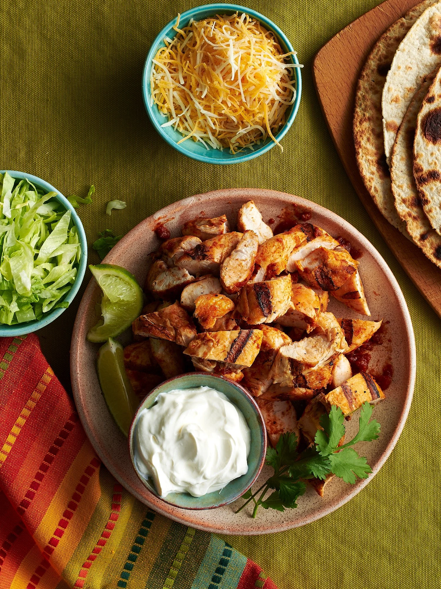 Food advertising photography by Dhanraj Emanuel — grilled chicken fajitas with lime, sour cream, and flatbreads on wooden board, shot for The Fresh Market. CPG and restaurant food photographer available nationwide.