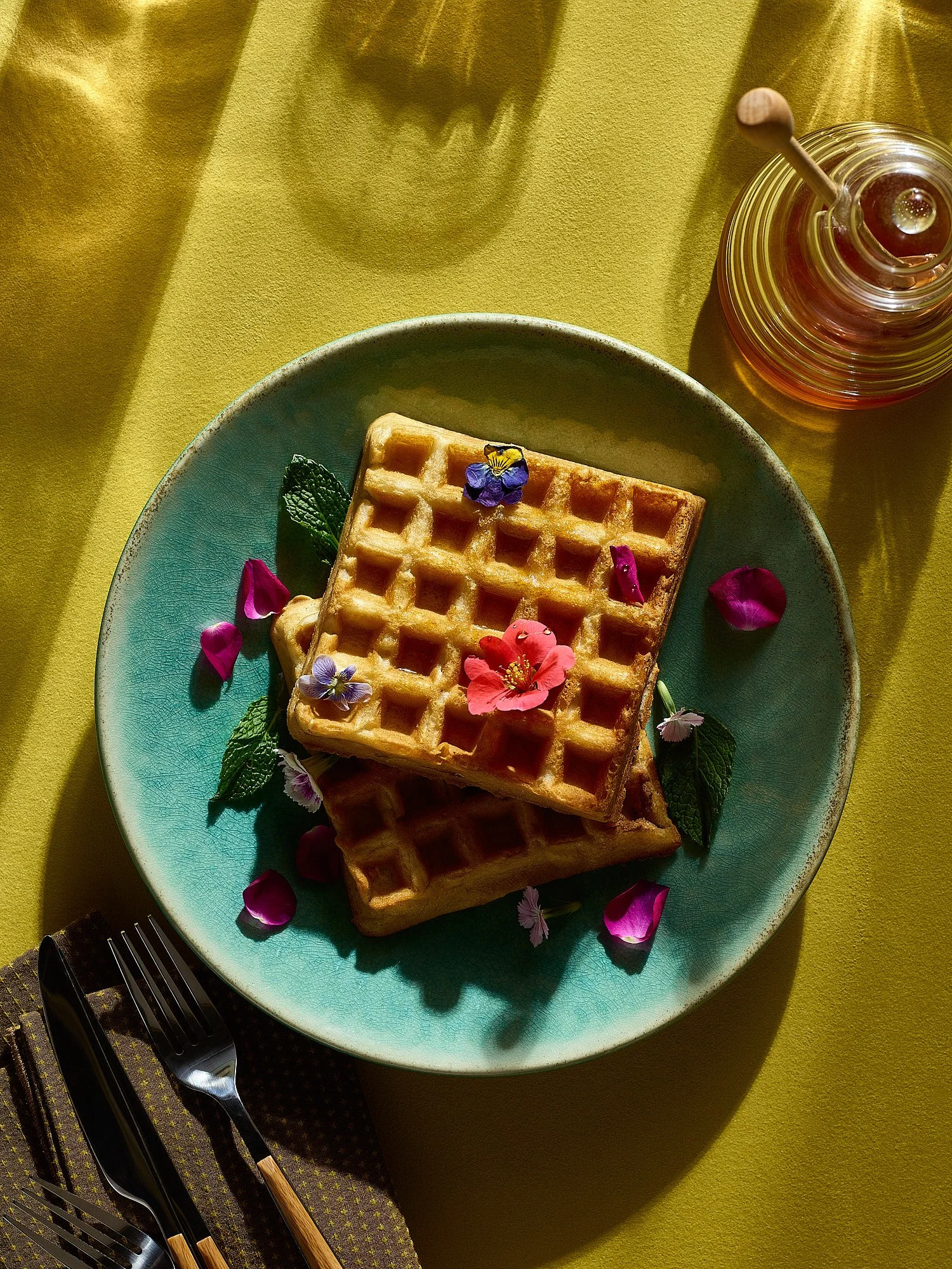 Commercial food photography by Dhanraj Emanuel — decorated waffles with edible flowers and honey on yellow background. Food photographer for CPG brands, packaging, and editorial clients nationwide.